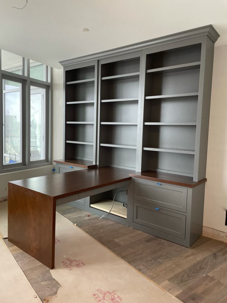 an empty room with two large bookshelves and a desk in front of the window