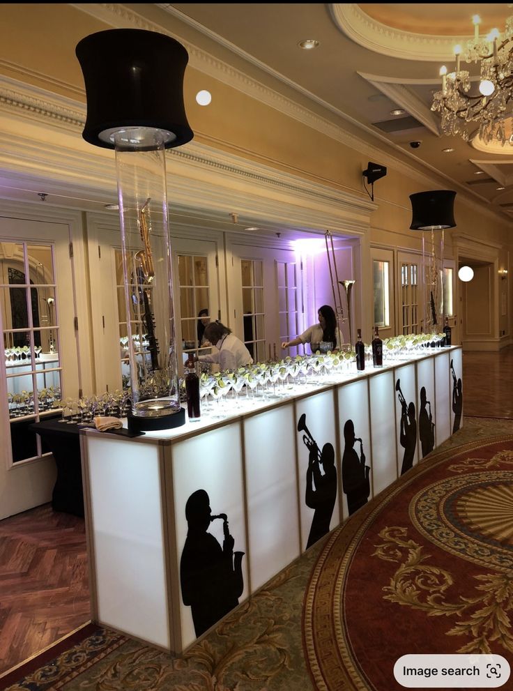 a long table with many items on it and people standing behind the counter in front of them