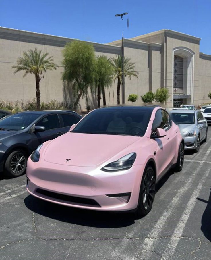 a pink tesla parked in a parking lot