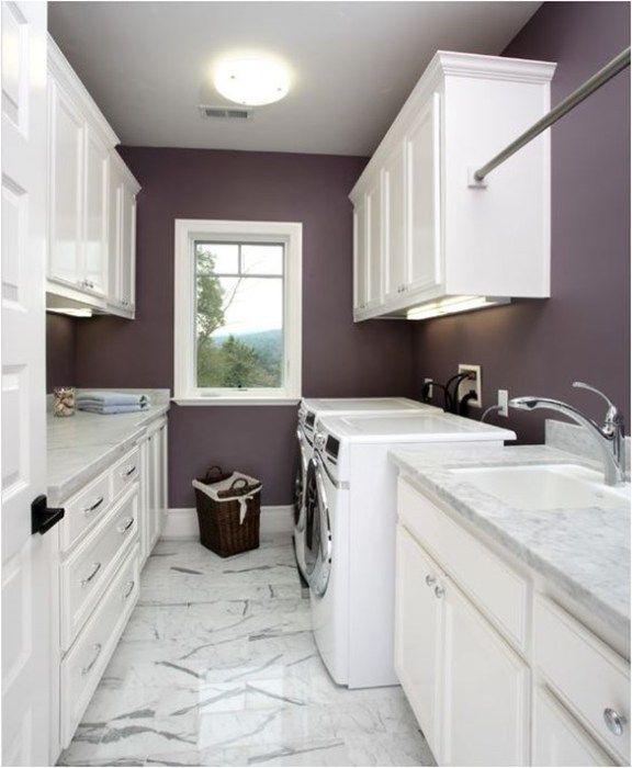 a kitchen with white cabinets and marble counter tops, along with a washer and dryer