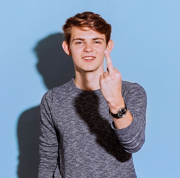 a young man is posing for the camera with his finger up in front of him