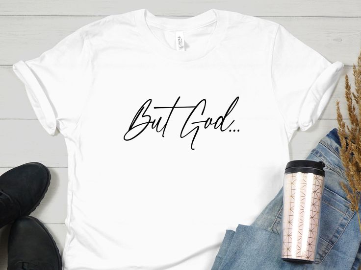 a t - shirt with the words but god on it next to a cup of coffee