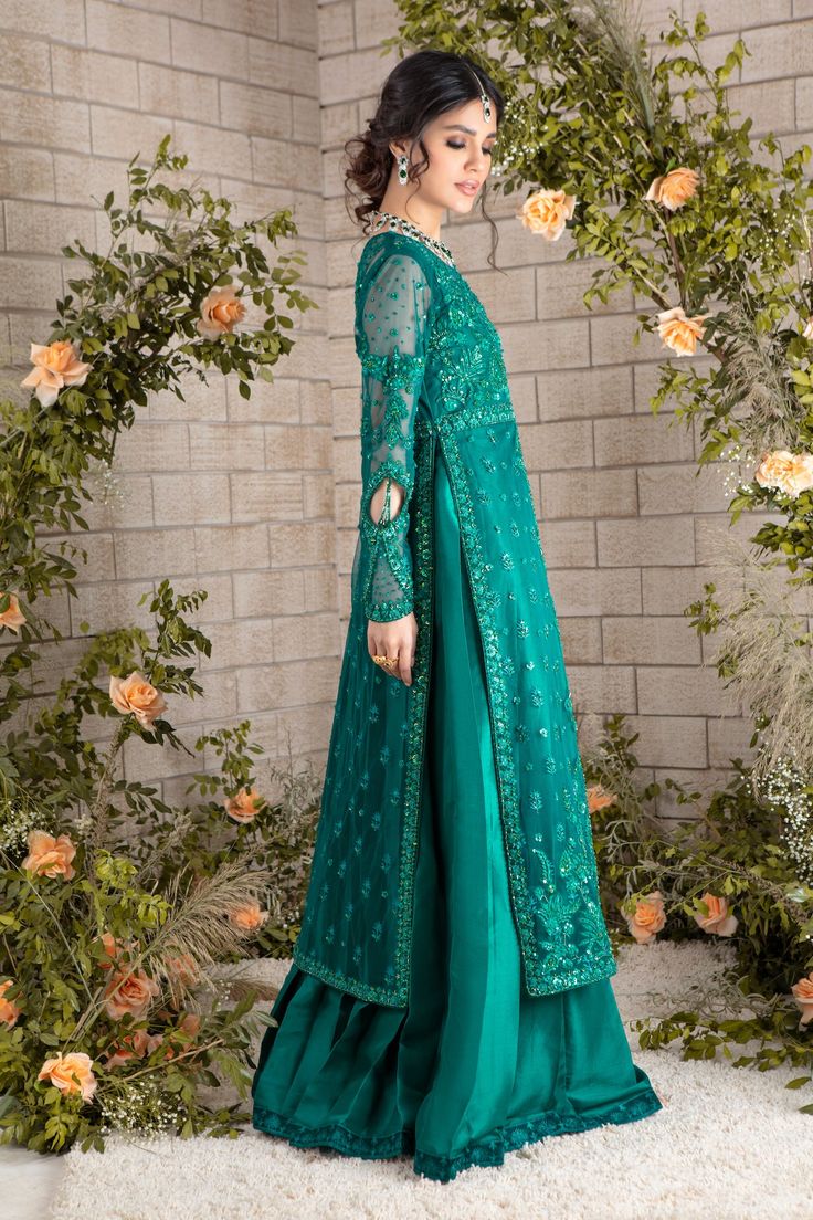 Emerald hued net front-open heavily embroidered jacket featuring glistening sequins, beads, pearls, crystals, stones and silk thread embroidery, attached to pure raw silk pleated gown, paired with heavily sequins embellished net dupatta, a wardrobe must have this wedding season. Gown Fabric: Net & Pure Raw Silk Length: Jacket length 48”, Gown Length 58” (customisable mention in order notes) Dupatta Fabric: Net Color: Emerald Green This is a two-piece outfit including gown & Draped dupatta. All o Anarkali Style Raw Silk Sherwani For Party, Hand Embellished Semi-stitched Gown For Eid, Hand Embellished Party Gown For Eid, Party Wear Semi-stitched Gown Hand Embellished, Party Wear Hand Embellished Semi-stitched Gown, Unstitched Organza Dress With Sequins, Designer Hand Embellished Gown For Eid, Raw Silk Long Sleeve Party Dress, Elegant Floor-length Sherwani With Sheer Dupatta