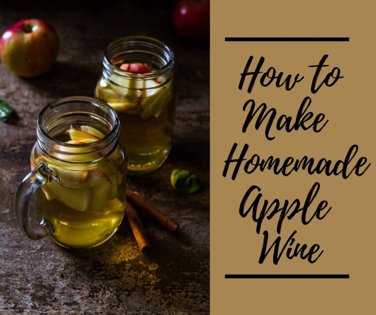 two jars filled with apple cider sitting on top of a table next to apples