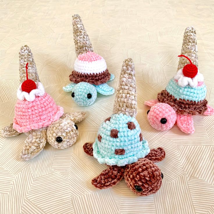 four crocheted stuffed animals with hats on them