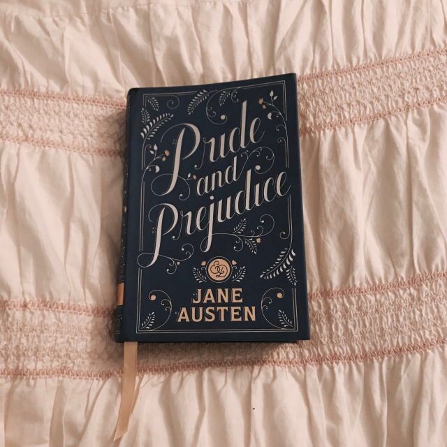 a book sitting on top of a bed next to a white comforter with pink trim