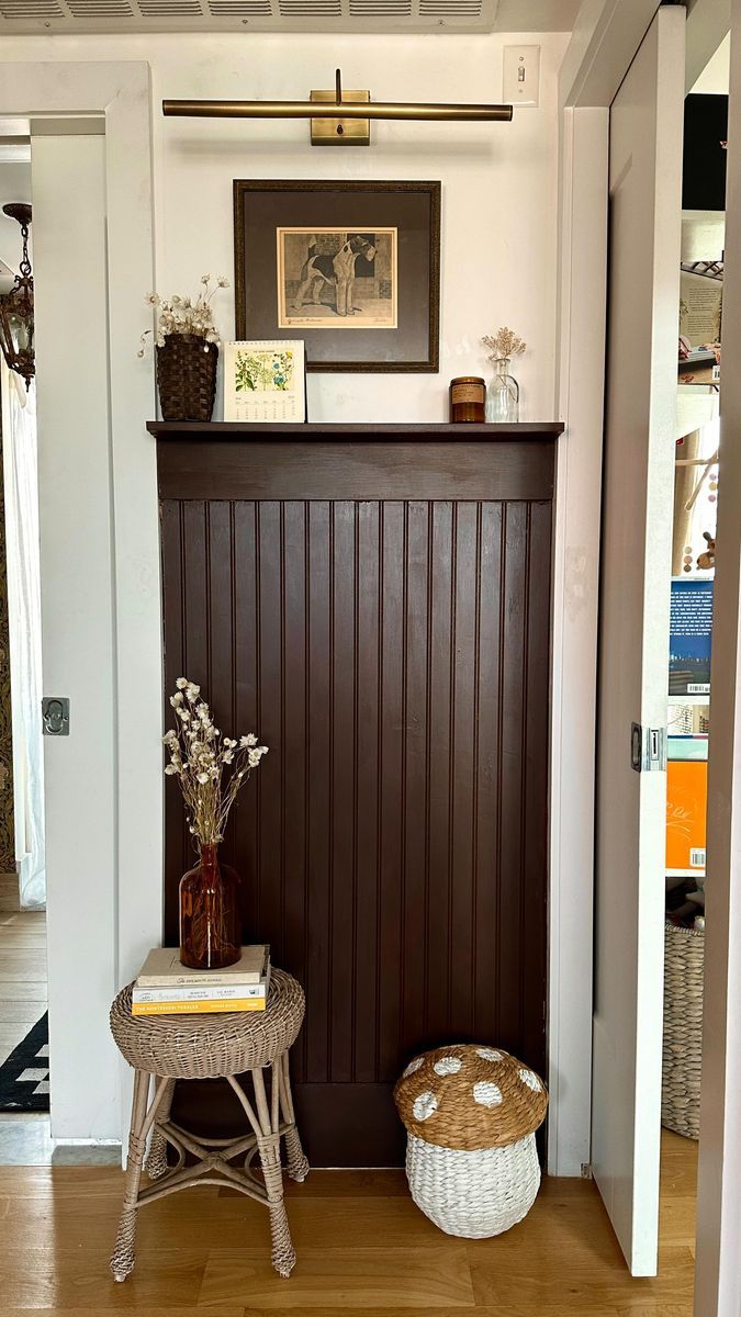 a room with a wooden paneled wall and basket on the floor next to it