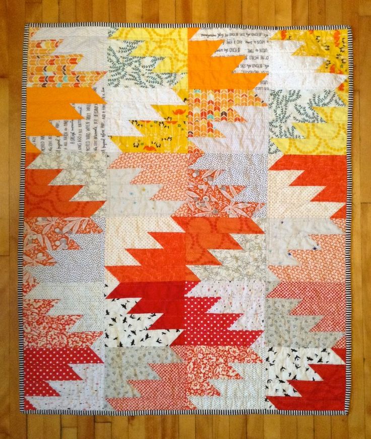 an orange and yellow quilt on a wooden floor