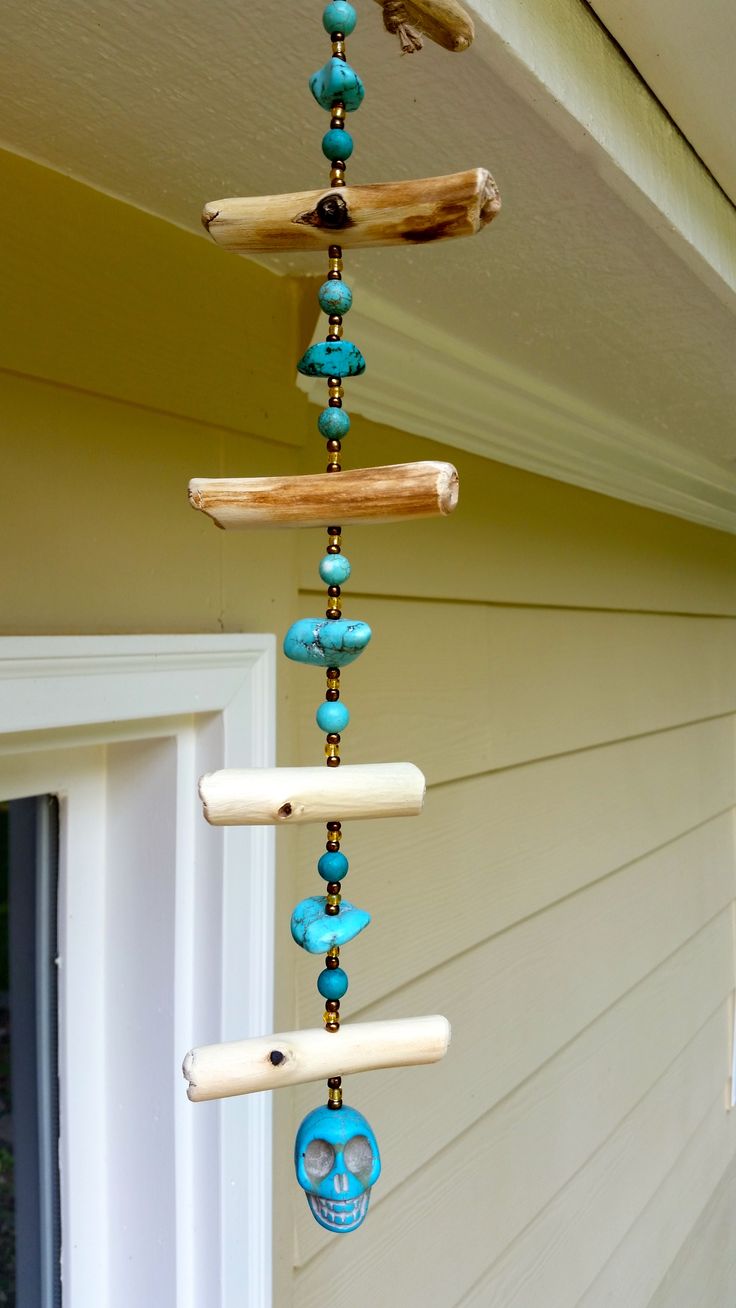 a wind chime hanging from the side of a house with blue beads on it