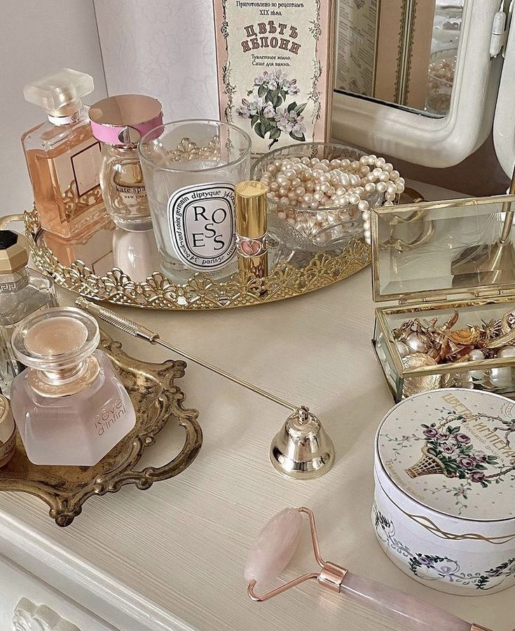 an assortment of beauty products on a white table with gold trimmings and pink flowers