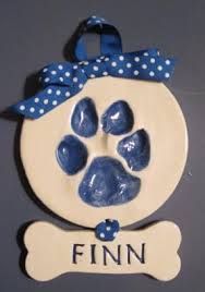 a ceramic ornament with a dog's paw and bone on it that says finn