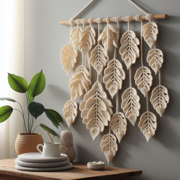 a crocheted wall hanging with leaves on it next to a potted plant