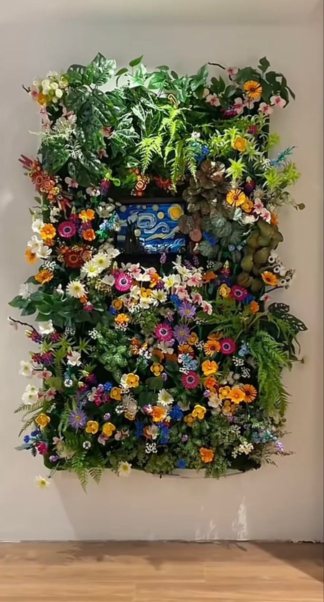 an arrangement of flowers is displayed on the wall