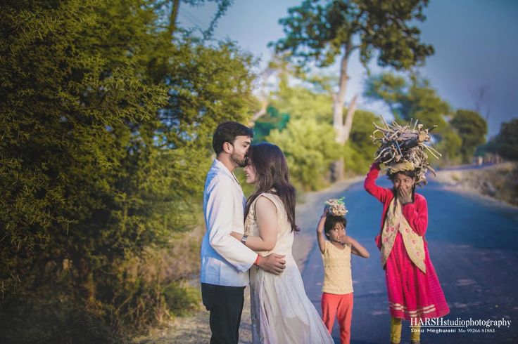 a family standing on the side of a road in front of some trees and bushes