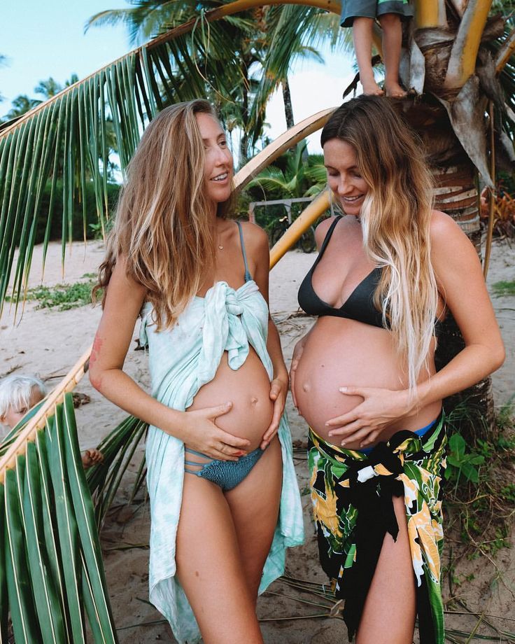 two women in bikinis standing next to each other on the beach with palm trees