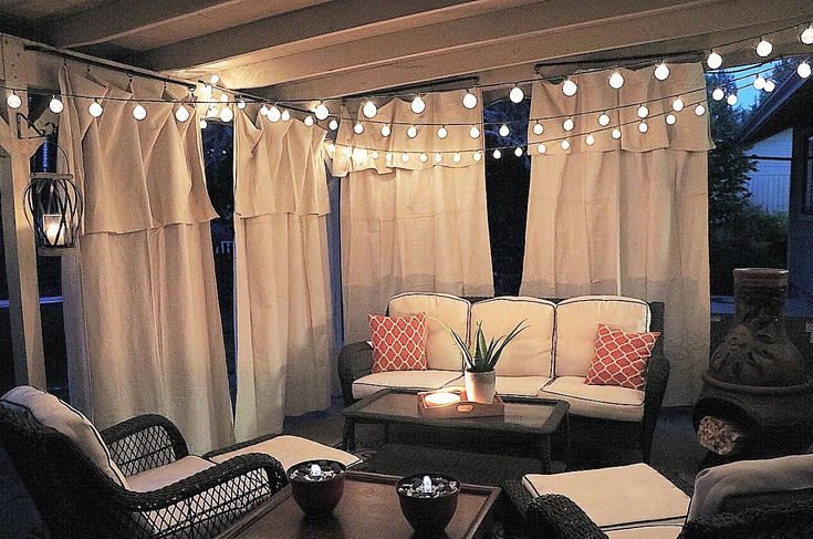 a living room filled with lots of furniture and lights hanging from the ceiling above it