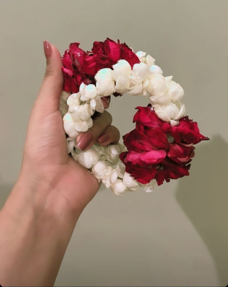 a hand holding a bunch of flowers in it's palm and the petals are white and red