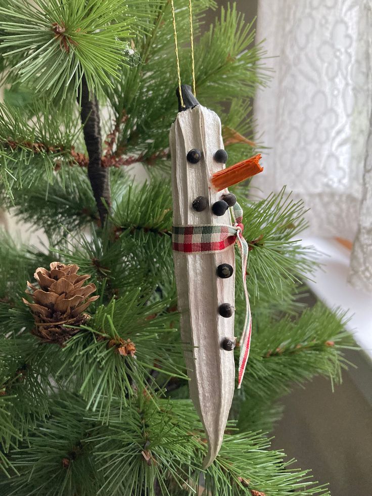 a snowman ornament hanging from a christmas tree