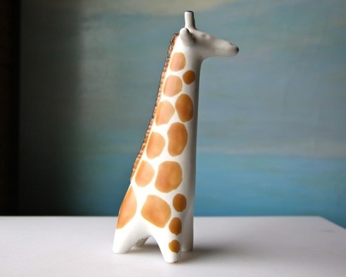 a giraffe figurine sitting on top of a white table next to a blue wall