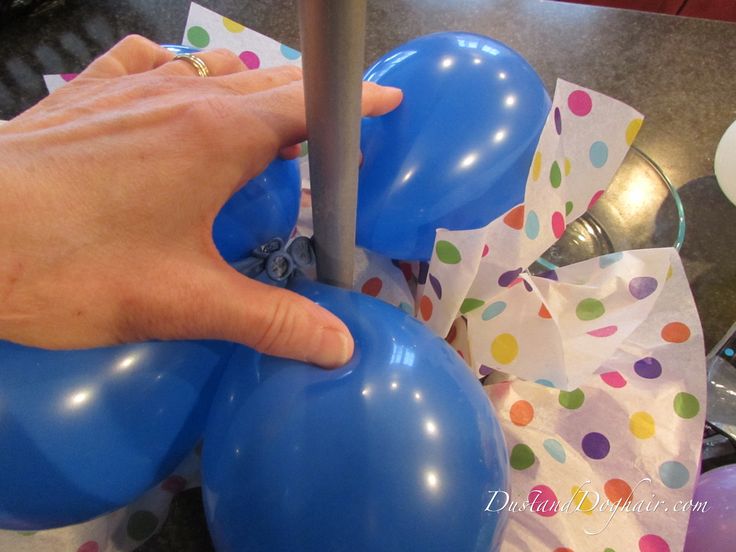 a person holding onto some balloons on top of a table with confetti and napkins