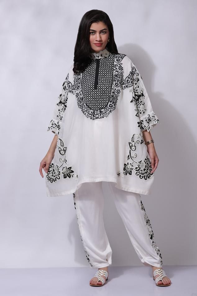 White high collared poncho style tunic with kiran dori, aari hand embroidery and patchwork. Paired with a pant.
Components: 2
Pattern: Embroidered
Type Of Work: Aari, Kiran Dori, Patch Work
Neckline: High collar
Sleeve Type: Three-quarter
Fabric: 50% Silk, 50% Cotton
Color: White
Other Details: 
Attached cotton lining
Closure: Hook and Eye
Occasion: Resort - Aza Fashions Patchwork Poncho, Lace Suit, Western Look, Dream Wedding Ideas Dresses, Poncho Style, Patch Work, White Silk, Pant Set, Embroidered Silk