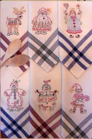 four white handkerchiefs with embroidered designs on them and a wooden spoon in the middle