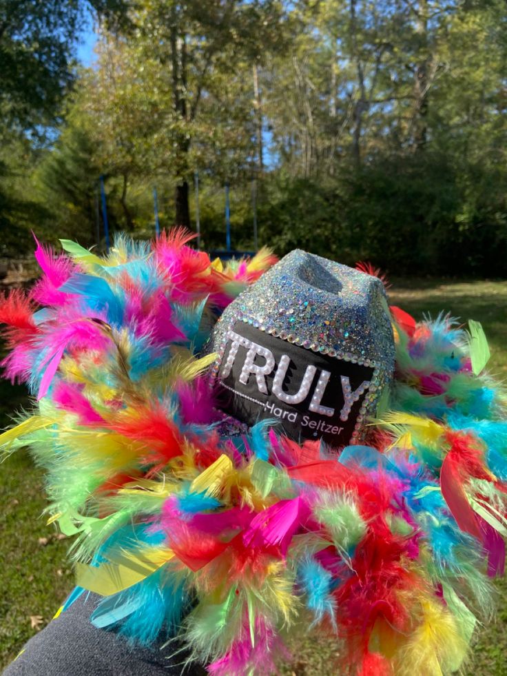 a person wearing a hat with colorful feathers on it and the word truly written on it