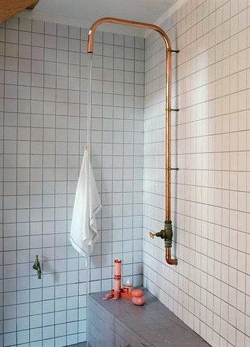 a white tiled bathroom with copper fixtures and pink tiles on the walls, along with a towel rack