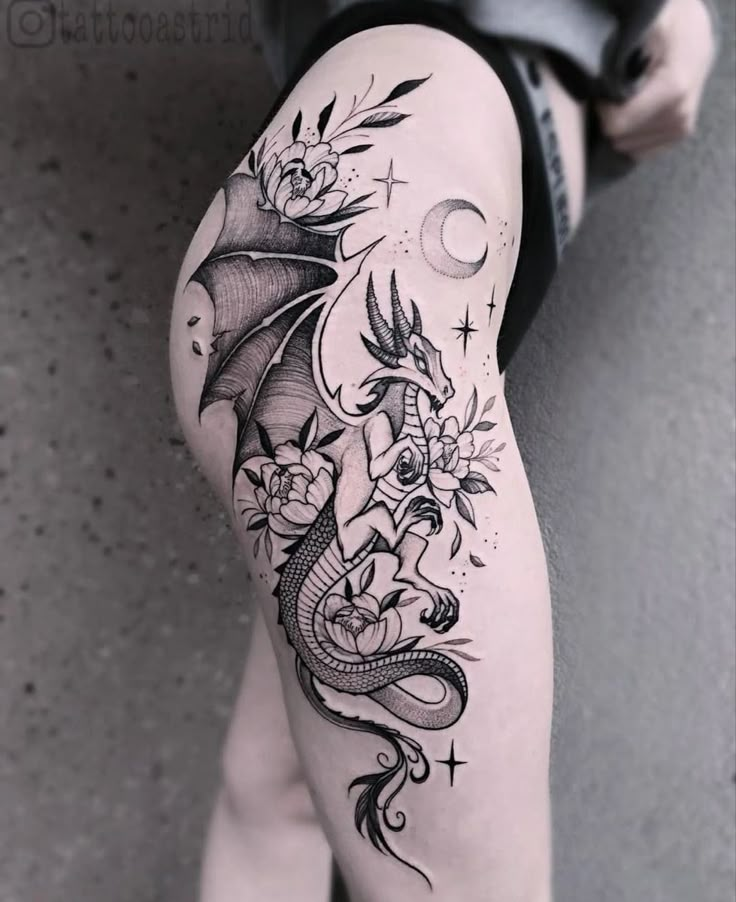 a woman's leg with a dragon and flowers tattoo design on the side of her thigh