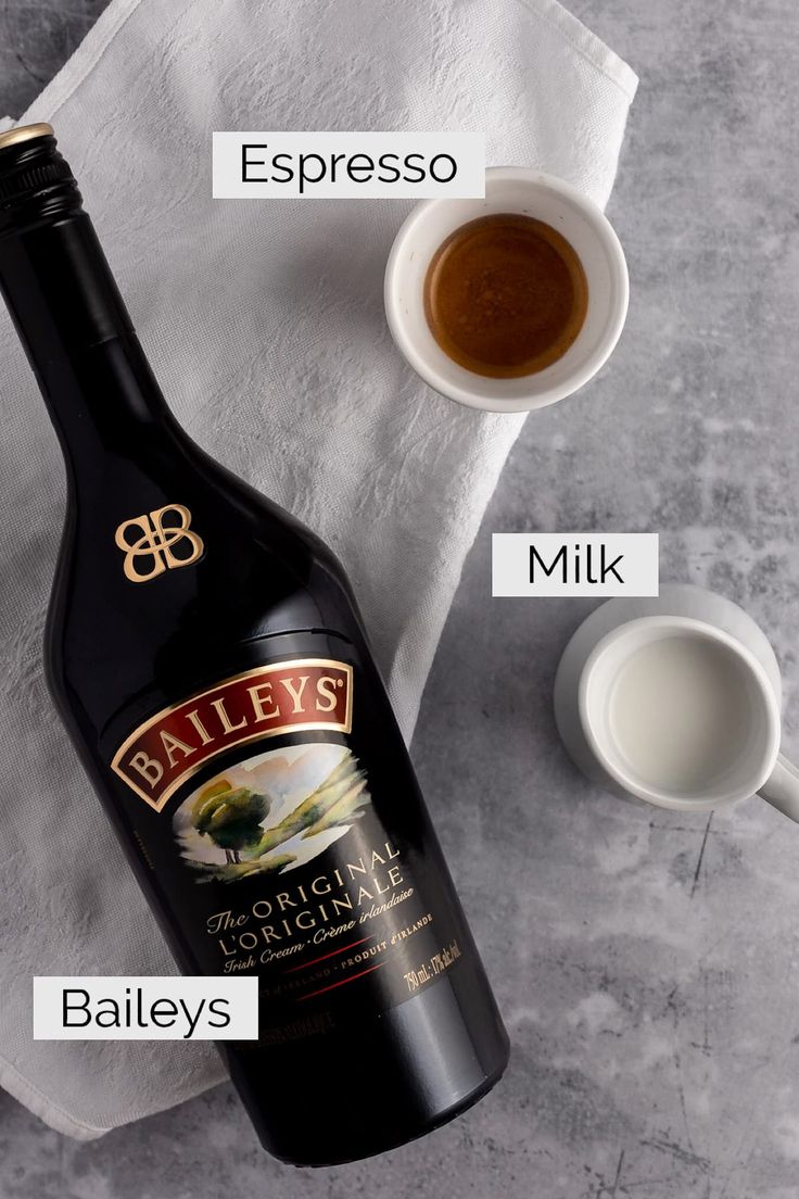 a bottle of bailey's coffee next to two cups