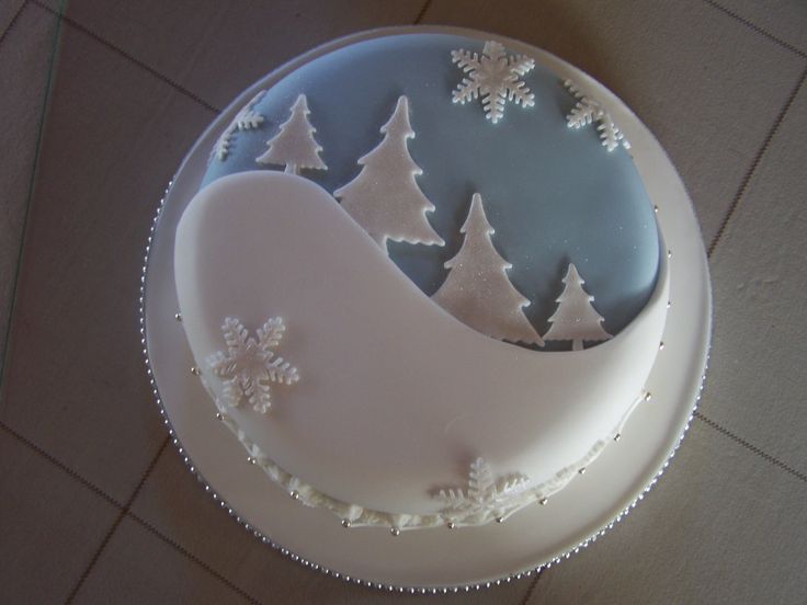 a frosted cake decorated with snowflakes and trees