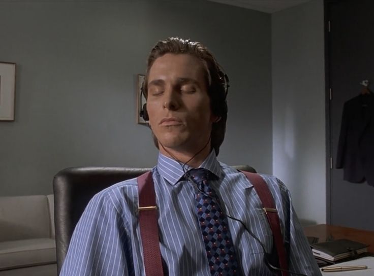 a man with headphones and suspenders sitting at a desk