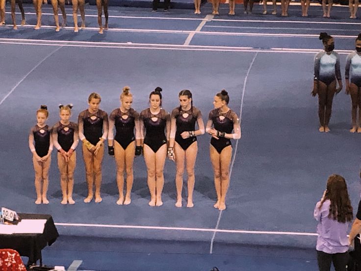 a group of young women standing on top of a blue floor next to each other