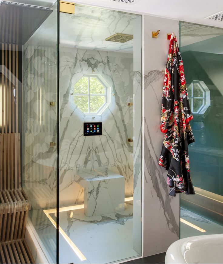 a bathroom with marble walls and flooring next to a bathtub filled with towels