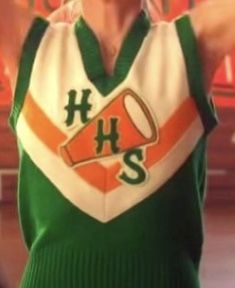 a man wearing a green and white shirt with an orange hhs logo on it