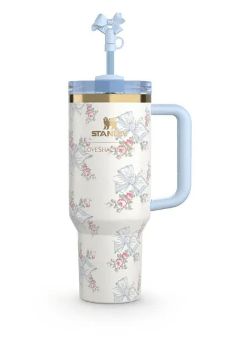 a white and blue travel mug with flowers on the side, in front of a white background