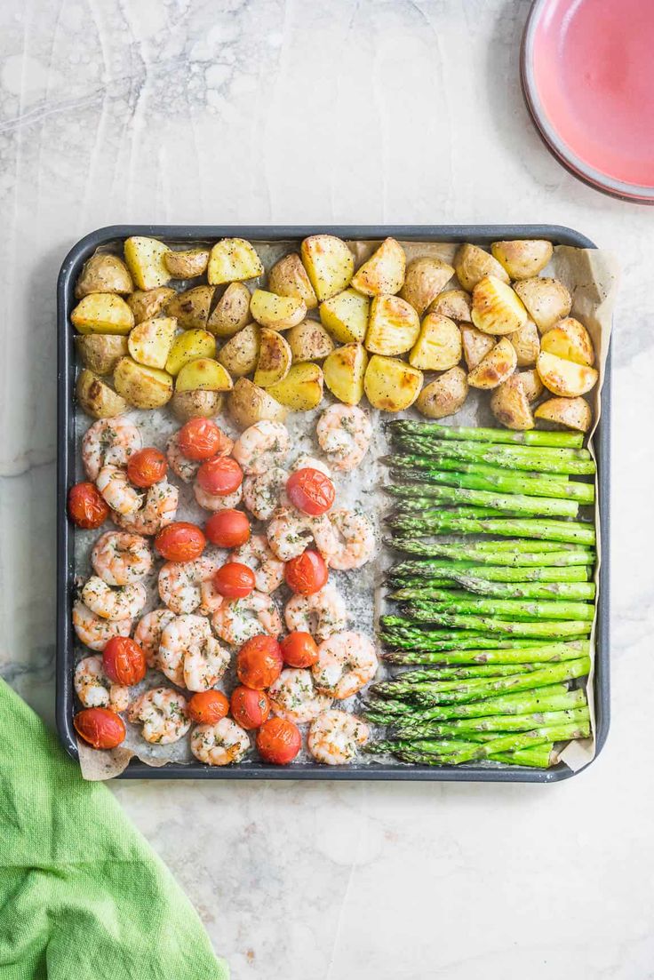 a tray filled with asparagus, potatoes and meatballs