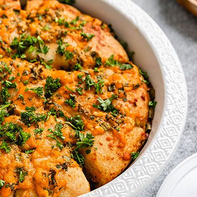 a casserole dish with chicken, cheese and parsley