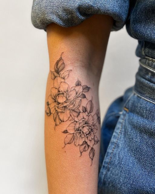 a woman's arm with a flower tattoo on the left side of her arm