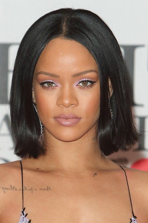 a close up of a person with short hair and purple eyeshadow wearing a black dress