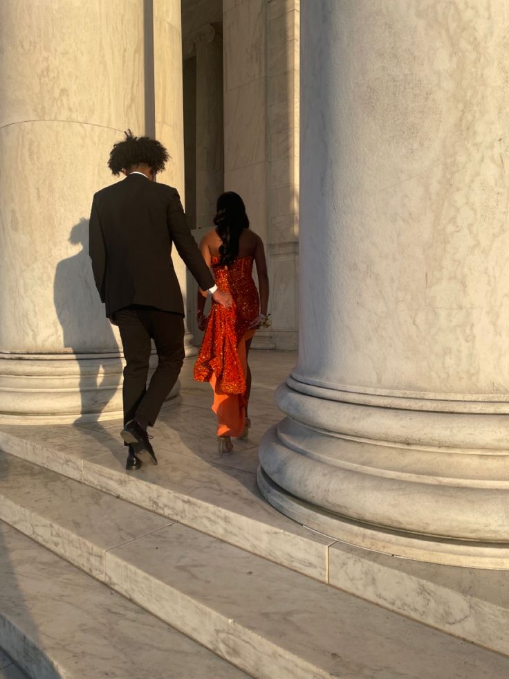 a man and woman are walking down the steps