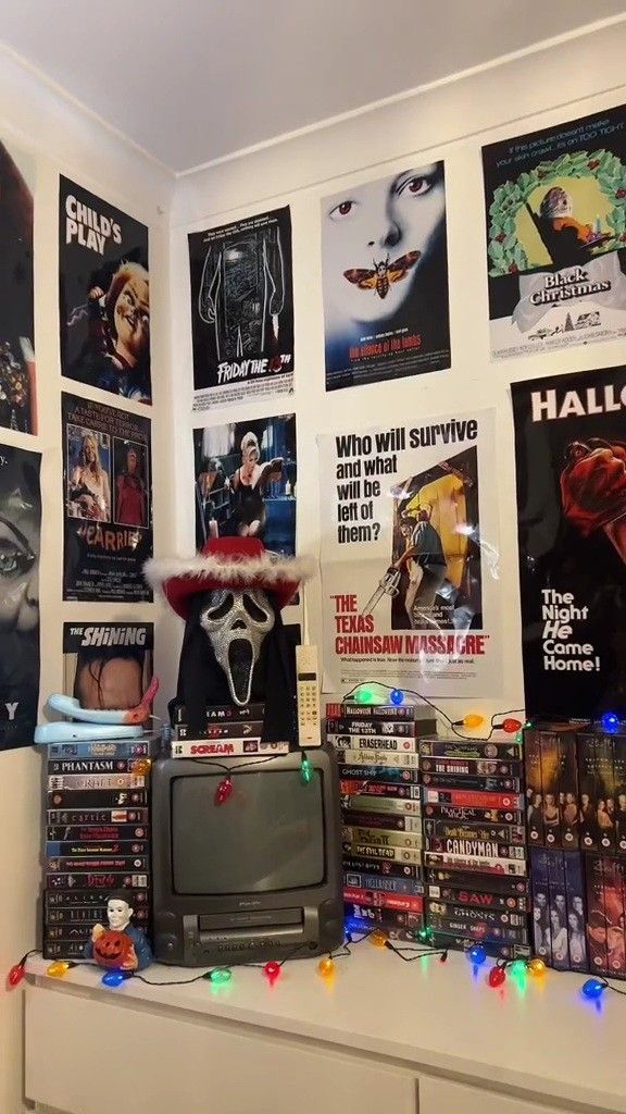 a tv sitting on top of a dresser next to a wall covered in movie posters