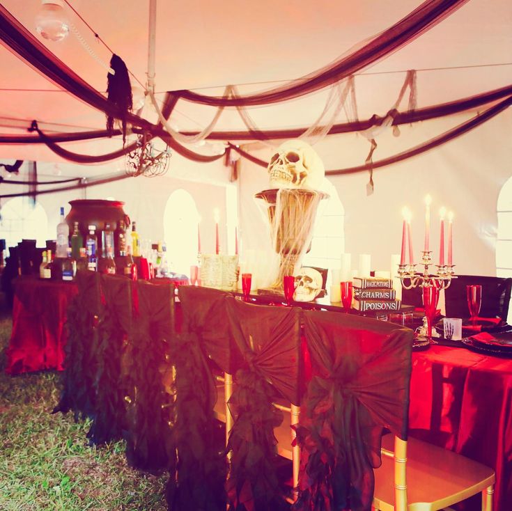 a long table covered in red cloths with candles and decorations on top of it