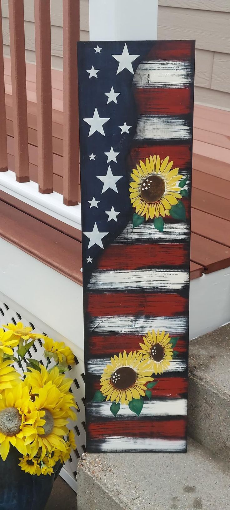 an american flag with sunflowers painted on it and flowers in the foreground