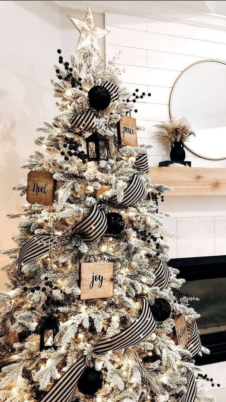 a white christmas tree decorated with black and silver ribbon, ornaments and tags on it