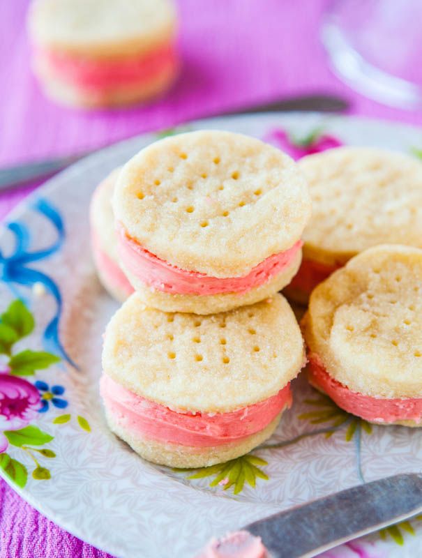 some cookies are stacked on top of each other with pink and white frosting in between them