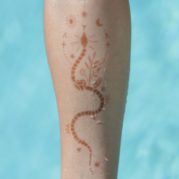 a close up of a person's leg with a tattoo on it and water in the background