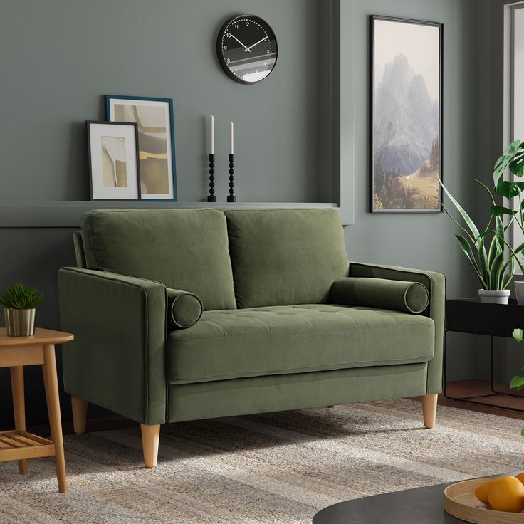 a living room with a green couch and clock on the wall