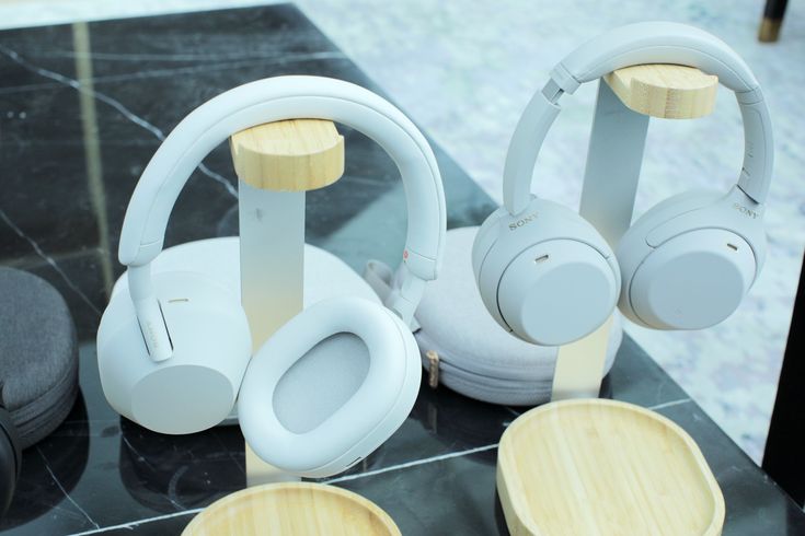 headphones are sitting on display in a store's glass case, with wooden bases