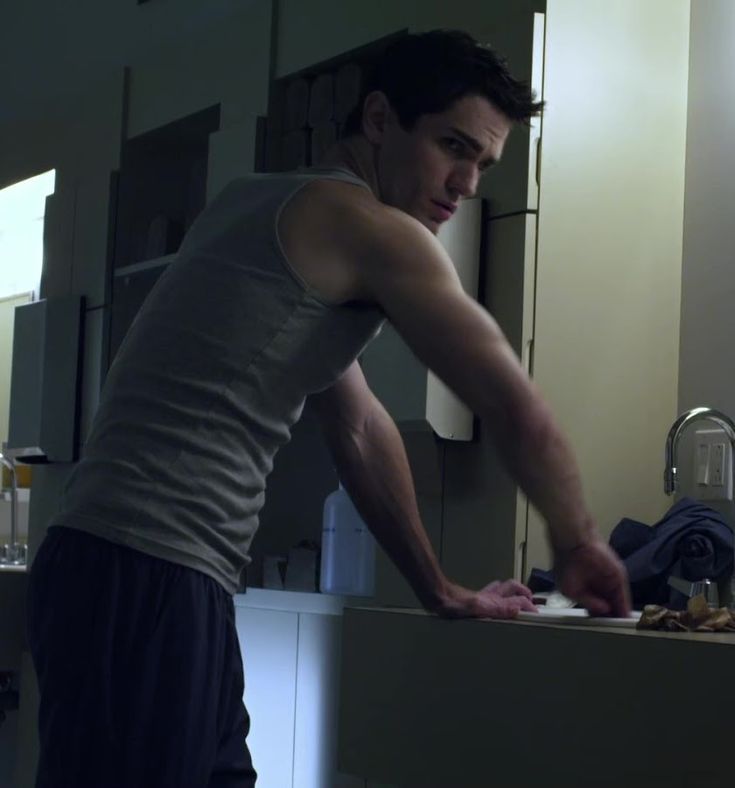 a man standing in front of a bathroom sink with his hands on the counter top